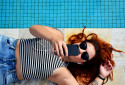 Une femme avec son smartphone au bord de la piscine (illustration).