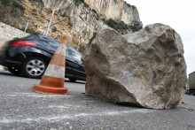 Une voiture passe derrière un rocher tombé après un éboulement. [Illustration]