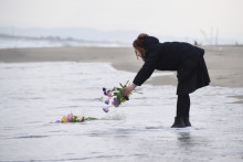 Une femme amène des fleurs à la mer, pour prier pour les victimes du tremblement de terre et du tsunami de 2011, à Sendai, au nord du Japon