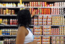 Une femme range des yaourts dans un rayon de supermarché (illustration)