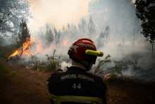 Un pompier prend position alors que la fumée s'élève d'un feu de forêt près de Louchats, à environ 35 km de Landiras en Gironde, le 18 juillet 2022.