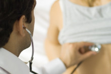 Médecin auscultant une patiente.