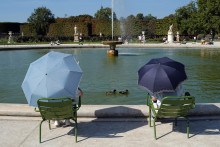 Deux personnes se protègent du soleil avec un parapluie alors qu'elles font face à la chaleur, au jardin des Tuileries à Paris, le 10 septembre 2023.