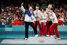 Les médaillés de double de tennis de table sud-coréens, nord-coréens et chinois posent ensemble sur le podium olympique à l'Arène Sud de Paris le 30 juillet 2024.