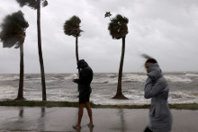 Des personnes marchent près de la baie de Tampa alors que l'ouragan Hélène se déplace vers le large le 26 septembre 2024 en Floride