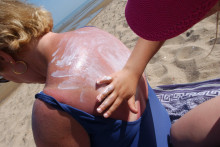 Une petite fille étale de la crème solaire sur le dos d'une amie sur la plage de Cabourg