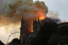 Un pompier utilise un tuyau pour étouffer les flammes et la fumée qui s'échappent du toit de la cathédrale Notre-Dame à Paris, le 15 avril 2019.