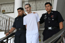 Le Français Tom Félix, accusé de possession et de trafic de cannabis, est escorté par des officiers de la police royale de Malaisie à la Haute Cour d'Alor Setar, le 16 juin 2025.