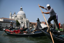 Des touristes profitent d'une balade en gondole sur le Grand Canal, dans la lagune de Venise, le 25 juin 2025.