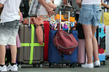 Le 27 juin 2025, des voyageurs en avion attendent avec leurs valises au comptoir d'enregistrement de l'aéroport de Leipzig-Halle, Allemagne..