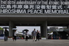 Des visiteurs marchent sous le signe de commémoration des 80 ans du bombardement d'Hiroshima (le 6 août 1945) au Hiroshima Peace Memorial.