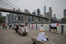 Des gens sont assis dans le Brooklyn Bridge Park, le 6 août 2025, à New York.