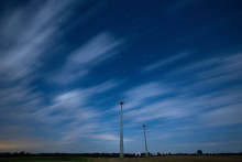 Des nuages passent au-dessus d'un parc éolien dans le ciel nocturne de Neundorf