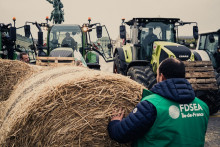 Des personnes tenant des bottes de paille devant des tracteurs lors d'une manifestation organisée par la FNSEA et les JA contre la concurrence déloyale et l'accord de libre-échange avec le Mercosur.