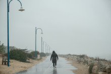 Une personne marche sous la pluie avant l'arrivée de la tempête Benjamin ans la station de La Palmyre (Charente-Maritime)