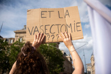 Une manifestante brandissant une pancarte appelant les hommes à faire des vasectomies