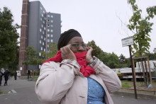 Une femme se bouche les oreilles alors que la sirène de la sécurité civile retentit depuis l'immeuble de la cité de l'Abreuvoir (arrière-plan), le 23 septembre 2012 à Bobigny, près de Paris.