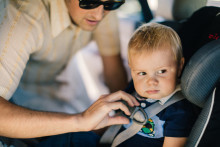 Un enfant attaché avec une ceinture de sécurité à l'arrière d'une voiture (image d'illustration)