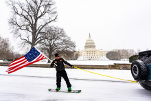 Un Américain, tracté par une voiture, fait du snowboard devant la Maison Blanche ce dimanche 25 janvier 2026.
