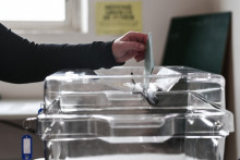 Une personne glisse un bulletin de vote dans une urne (Illustration).