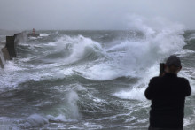Un homme prend une photo alors que d'énormes vagues et des vents violents causés par la tempête Benjamin frappent le port de Plobannalec-Lesconil