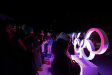 Des passants posent devant les anneaux olympiques le 30 janvier 2026 à Courchevel