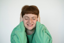 Gros plan d’une femme stressée, les yeux fermés, se bouchant les oreilles avec ses mains. (Illustration)