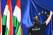 Un employé ajuste un drapeau européen à côté de drapeaux hongrois au centre de congrès et d'expositions HUNGEXPO de Budapest, en Hongrie, le 13 avril 2026