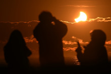 Des gens observent une éclipse solaire partielle à New Brighton, une banlieue côtière de Christchurch en Nouvelle-Zélande, le 22 septembre 2025