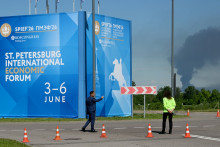 Des personnes se tiennent devant des banderoles à l'effigie du Forum économique international de Saint-Pétersbourg (SPIEF) tandis qu'une fumée noire s'élève au loin à Saint-Pétersbourg, en Russie, le 3 juin 2026.