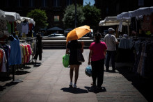 Des piétons se promènent dans les rues de Toulouse, un parapluie à la main pour se protéger du soleil, le 27 mai 2026.