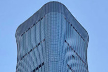 Un trou est visible (à droite) sur la façade de la tour CITIC à Pékin, le 26 juin 2026, après qu'un témoin a signalé la présence de débris d'avion au pied du plus haut bâtiment de la ville.