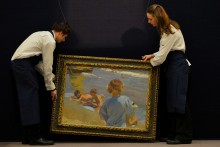Des employés devant un tableau intitulé "Niños en la Playa" (1916), œuvre du peintre espagnol Joaquín Sorolla, à Londres le 17 mai 2013.