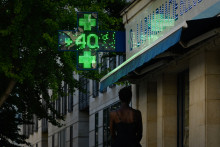 Des piétons passent devant la croix verte lumineuse d'une pharmacie affichant 40°C à Bordeaux, le 6 juillet 2026 (Illustration).