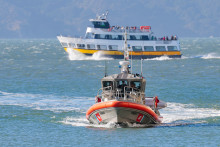 Un navire des garde-côtes américains pénètre dans la crique de Gashouse Cove alors que les recherches se poursuivent pour retrouver deux personnes disparues après le chavirage d'un bateau ponton le 14 juillet 2026 à San Francisco, en Californie.