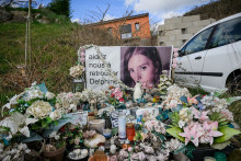 Cette photographie, prise le 6 mars 2025, montre des bougies et des fleurs déposées devant la maison de Delphine (portrait) et de Cédric Jubillar à Cagnac-les-Mines.