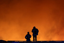 Des pompiers contemplent les flammes de l'incendie qui fait rage en Gironde, au nord du bassin d'Arcachon, le mercredi 22 juillet.