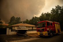 Un camion de pompiers passant devant une maison avec de la fumée s'élevant de l'incendie à Lège-Cap-Ferret le 23 juillet 2026.