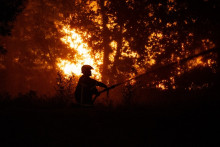 Un pompier arrose une forêt en feu près d'une zone résidentielle lors d'un incendie de forêt près de Lège-Cap-Ferret, dans le sud-ouest de la France, le 23 juillet 2026.