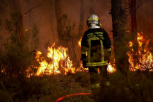 Un pompier se tient devant les flammes alors qu'un incendie de forêt fait rage à Saint-Jean-d'Illac, à une trentaine de kilomètres de Bordeaux, le 26 juillet 2026.