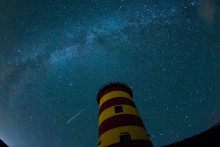 Une étoile filante traverse le ciel nocturne derrière le phare en Pilsum, au nord-ouest de l'Allemagne lors 13 août 2015