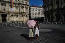 Deux piétons se tiennent sous un parapluie pendant une vague de chaleur à Lyon, le 24 juin 2026.