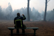 Un pompier boit de l'eau au milieu de la fumée à Claouey, au nord du bassin d'Arcachon, le 29 juillet 2026.