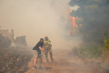 Deux personnes luttant contre un feu à l'ouest d'Athènes, le 2 août 2026
