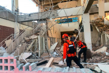 Les secours cherchant les décombres d'un bâtiment effondré après un séisme de magnitude 7,7 en Indonésie le 15 août 2026.