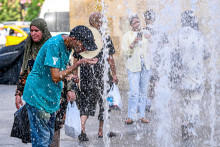 Le 24 août 2026, des passants se rafraîchissent sous les jets d'eau d'une fontaine située à l'entrée de la médina (vieille ville) de Tunis.