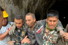 Des membres des forces de sécurité transportant un ressortissant chinois (à droite) secouru du tunnel d'audit n° 4 du chantier du projet hydroélectrique d'Upper Trishuli-1, au Népal.