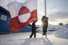 Des hommes hissent un drapeau groenlandais près des bureaux de vote à Nuuk, au Groenland, le 24 mars 2026, lors des élections législatives au Danemark.