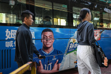 Des passants déambulent devant un bus à l'effigie de la star du football français Kylian Mbappé en Chine