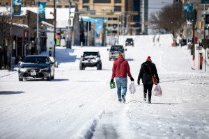 Des gens portent des provisions depuis une station-service le 15 février 2021 à Austin, Texas.